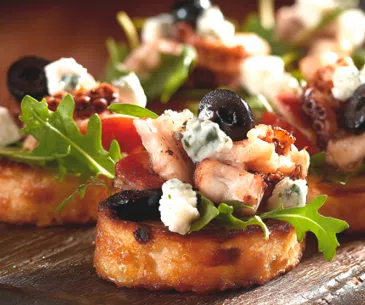 Exzellentes Catering Geröstete Brotscheiben belegt mit Garnelen, Blauschimmelkäse, schwarzen Oliven und Rucola