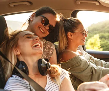 DEGENER Infotage Drei lachende Frauen mit Sonnenbrillen genießen eine gemeinsame Autofahrt bei sonnigem Wetter